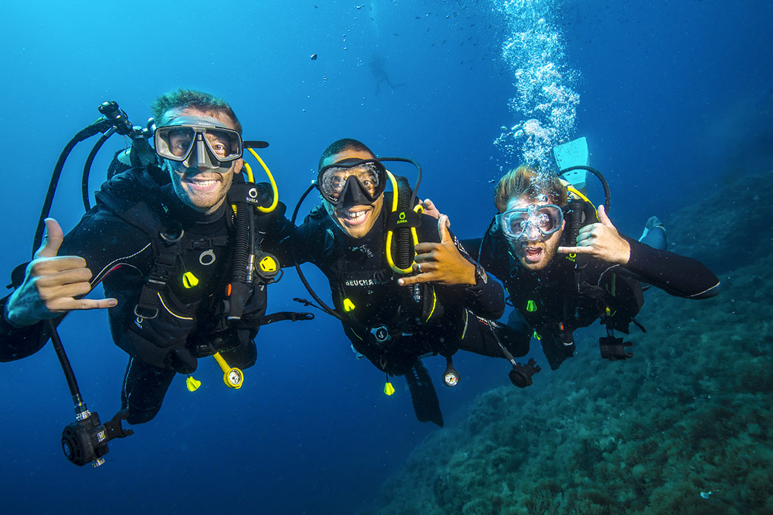 Trois plongeurs prenant la pose sous l'eau